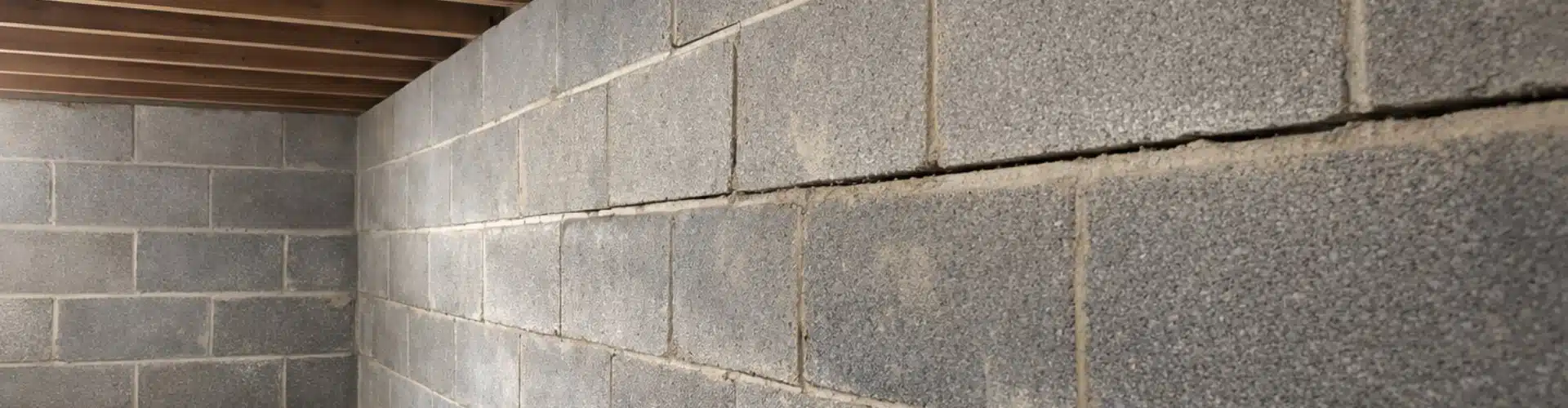 Bowing concrete block basement wall in a Northern Virginia home, showing a horizontal crack along the mortar joint.