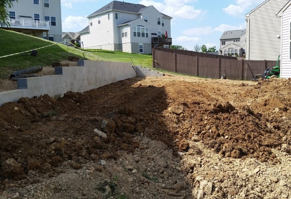 Excavated red clay soil beside a residential foundation in Northern Virginia, showing expansive clay conditions causing movement.