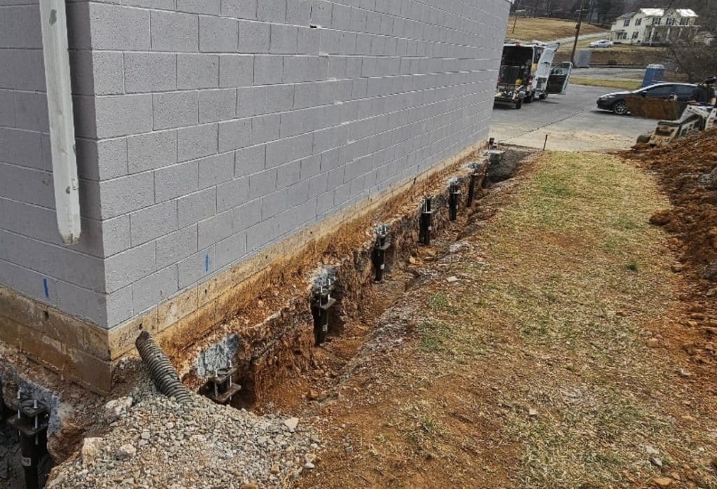 Push piers installed along a residential foundation wall in Northern Virginia, providing permanent stabilization on clay soil.