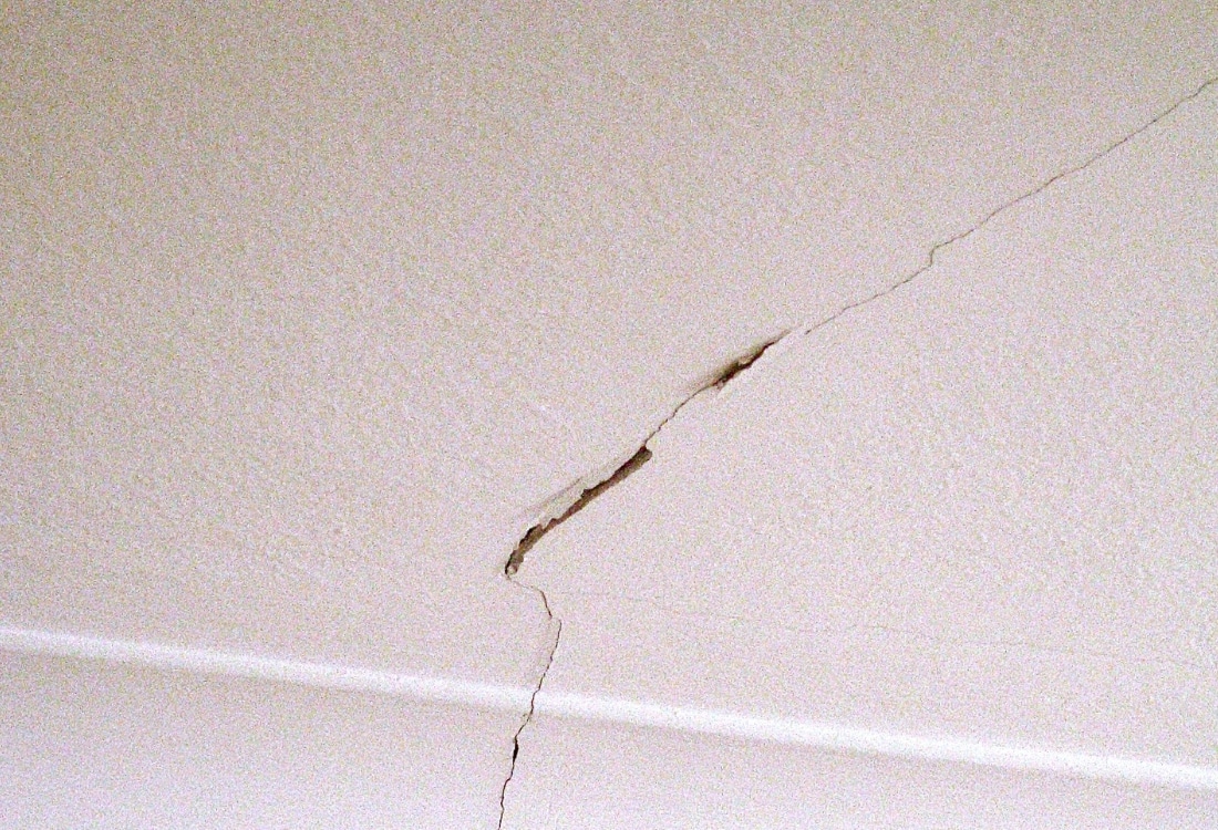 Diagonal ceiling crack on plaster ceiling indicating structural movement and possible foundation settlement in the home