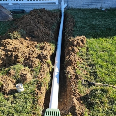 Installed downspout extension directing roof runoff water away from the home foundation to prevent basement wall seepage.
