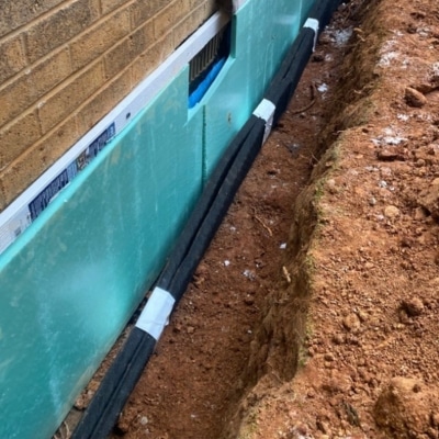Installed exterior waterproof membrane on exposed foundation wall to block groundwater from penetrating the basement wall.