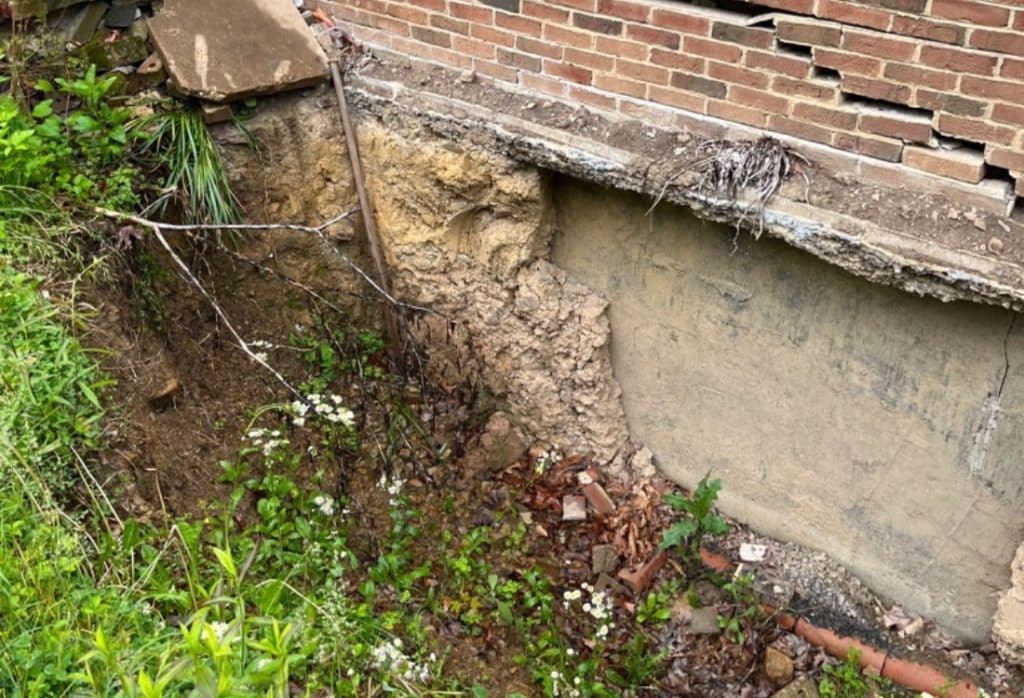 Foundation corner showing significant soil erosion and settlement damage caused by clay soil movement in the home.