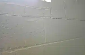 Painted concrete block basement wall with horizontal cracks, a sign of a bowing basement wall in Ashburn, VA.
