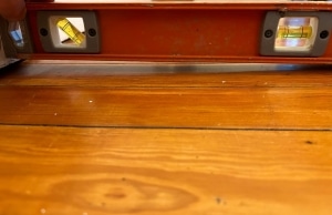 A level tool on the floor showing an uneven surface, a sign of cracks in the concrete wall in Flint Hill, VA.