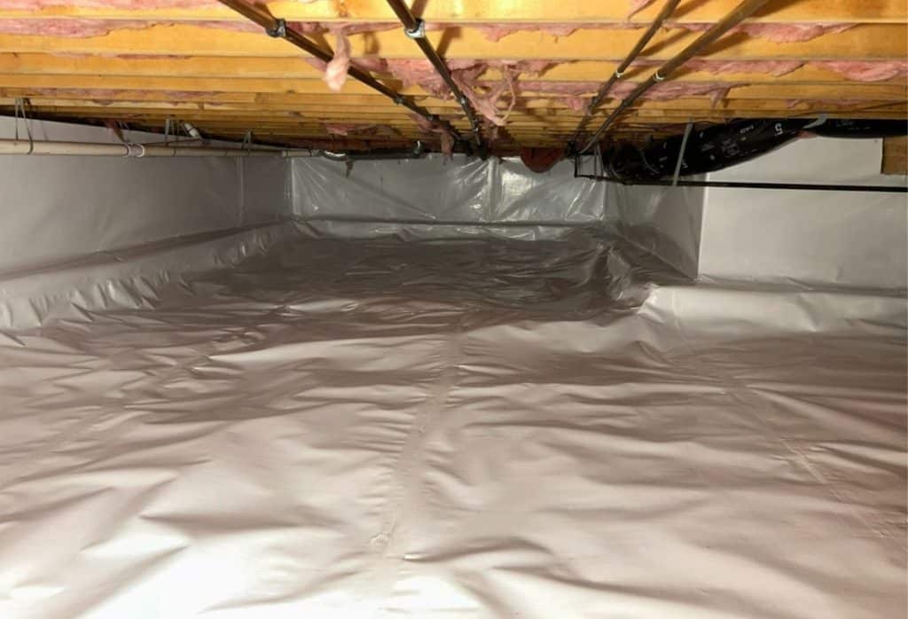 Crawl space vapor barrier in Northern Virginia showing gray polyethylene plastic sheeting installed on floor and foundation walls.