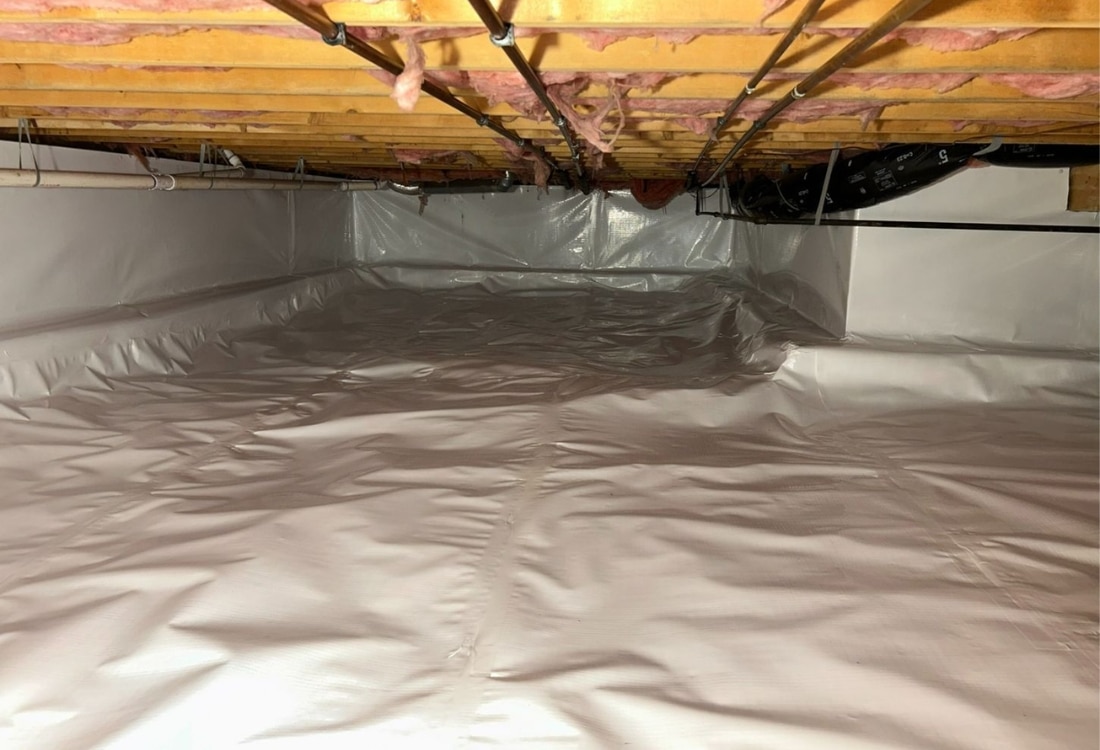 Crawl space vapor barrier in Northern Virginia showing gray polyethylene plastic sheeting installed on floor and foundation walls.