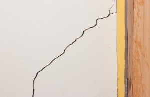 Crack running down basement wall showing foundation damage that allows water seepage and staining in Brambleton, VA.