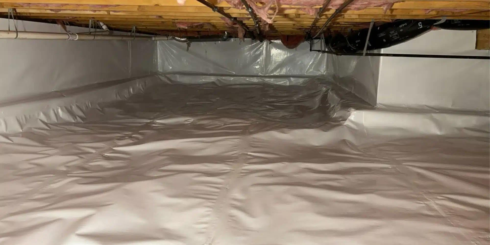 White polyethylene plastic sheeting on the crawl space floor showing what a vapor barrier in a crawl space looks like in Winchester, VA.