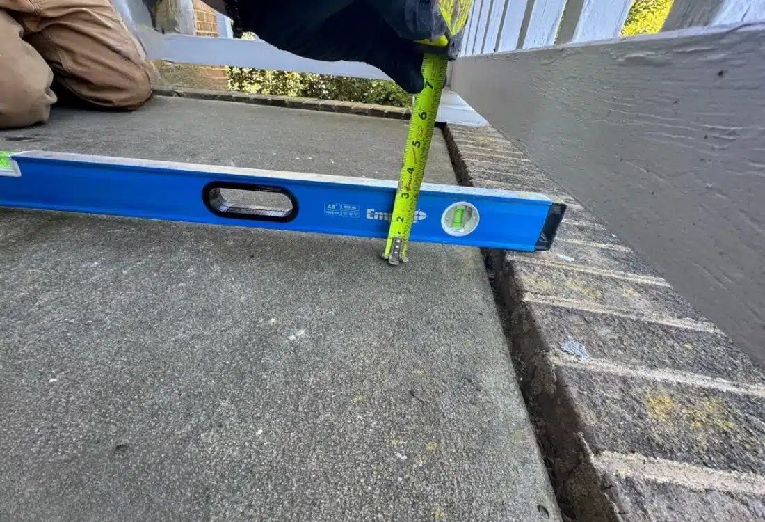 Sunken front porch concrete slab 2 inches below brick border before polyurethane foam lifting in Fredericksburg, VA.