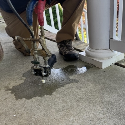LUX technician injecting polyurethane foam into a concrete porch slab to fix a sinking porch in Flint Hill, VA.