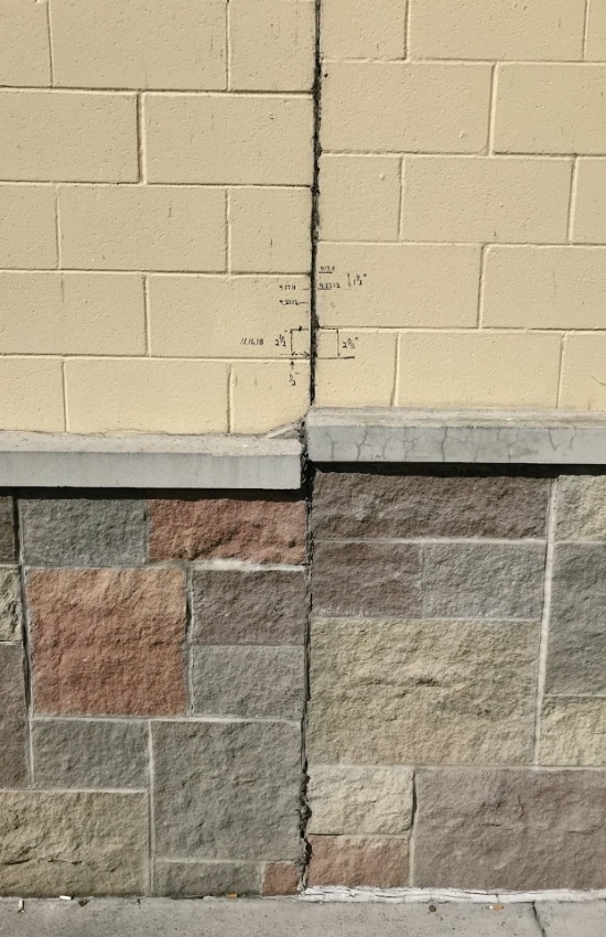 Basement wall crack with measurement markings showing crack width indicating structural stress that needs repair in Winchester, VA.