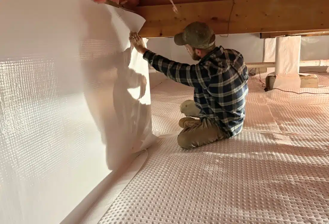 LUX technician installing vapor barrier during crawl space encapsulation to seal the area and reduce energy cost in Fairfax, VA.