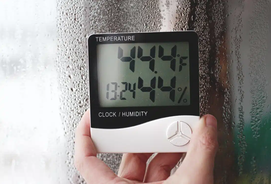 Humidity meter in window showing high moisture and condensation, causing a musty basement smell in Charles Town, WV.