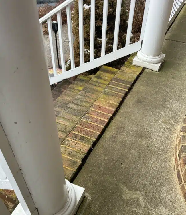 Sunken brick porch step separated from concrete surface showing an active sinking porch problem in Northern Virginia.
