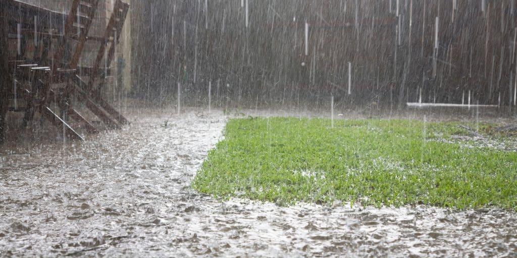 Standing water pooling around a house lawn in Northern Virginia during heavy rain causing drainage problems and foundation risk.