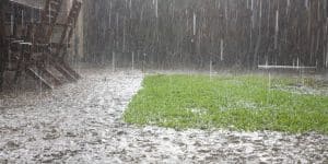 Standing water pooling around a house lawn in Northern Virginia during heavy rain causing drainage problems and foundation risk.