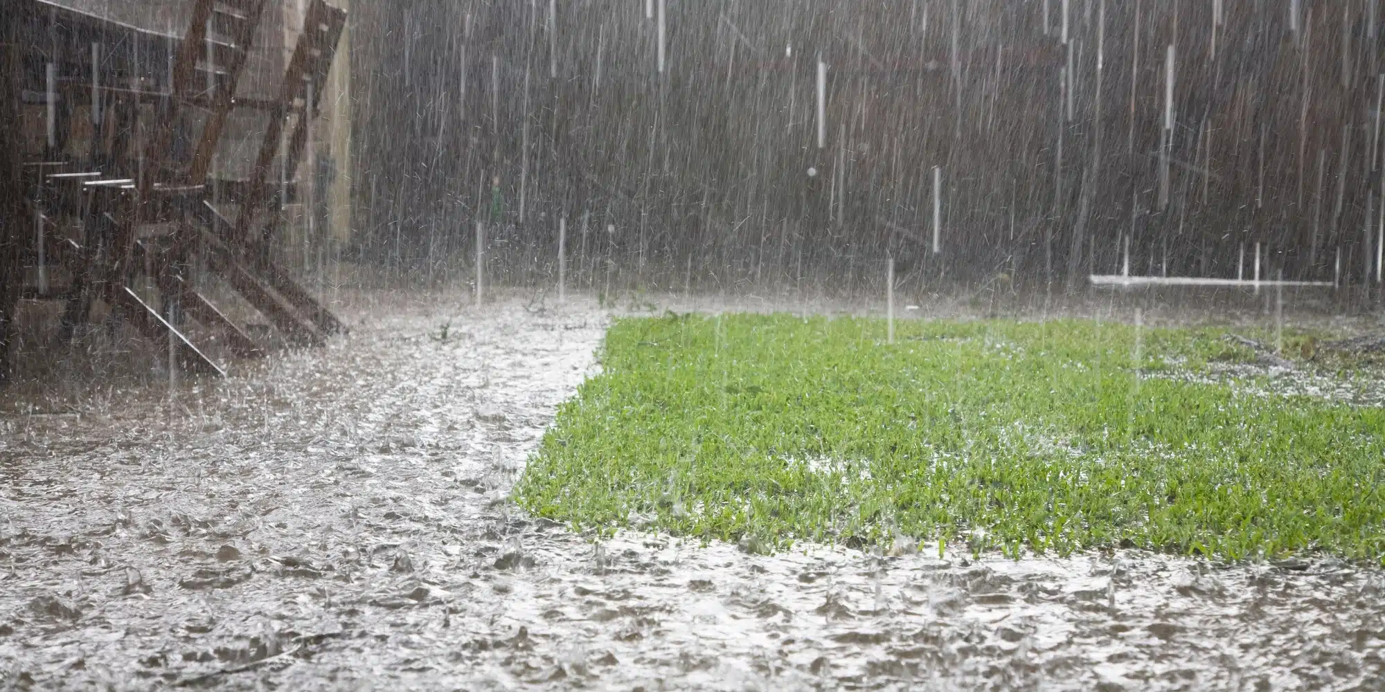 Standing water pooling around a house lawn in Northern Virginia during heavy rain causing drainage problems and foundation risk.