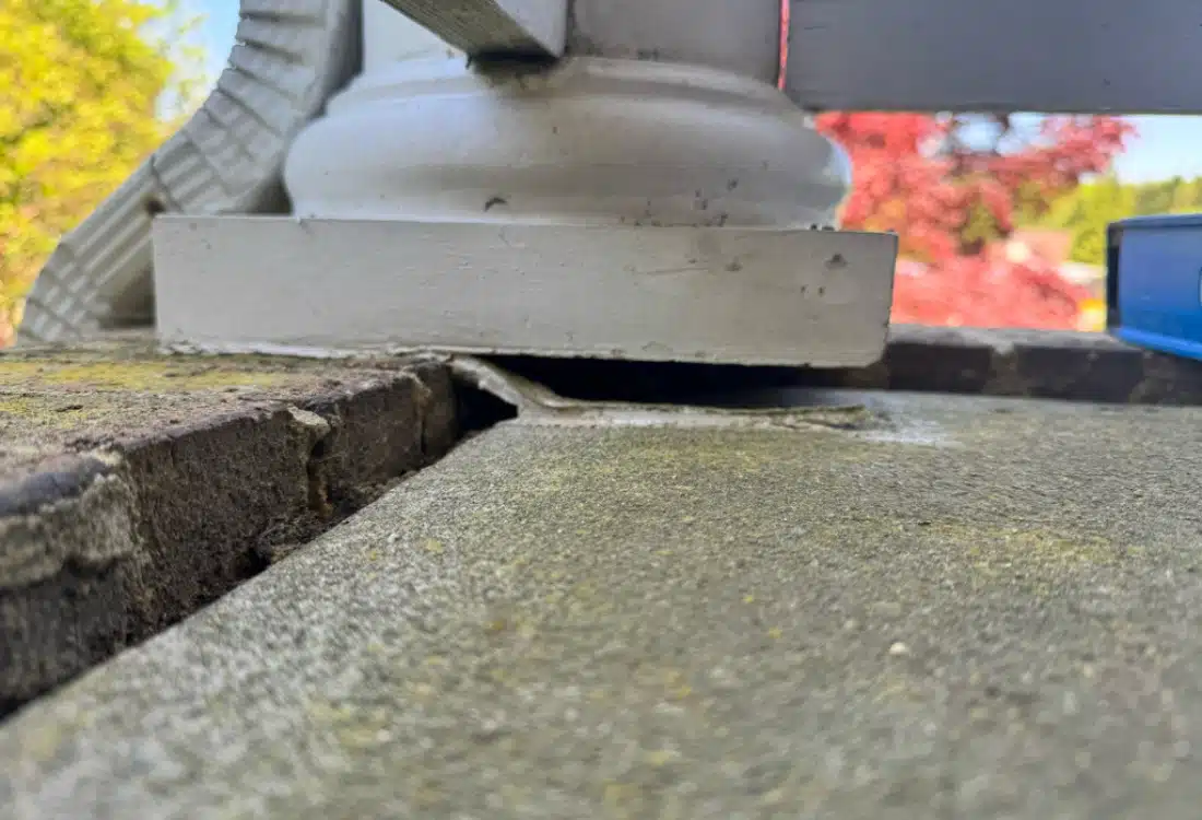 Sunken porch concrete slab pulled away from brick border with column base lifted before concrete leveling in Fredericksburg, VA.