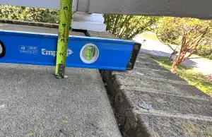 Level tool on concrete porch surface showing measurable tilt and uneven slope from sinking porch settlement IN Reston, VA.
