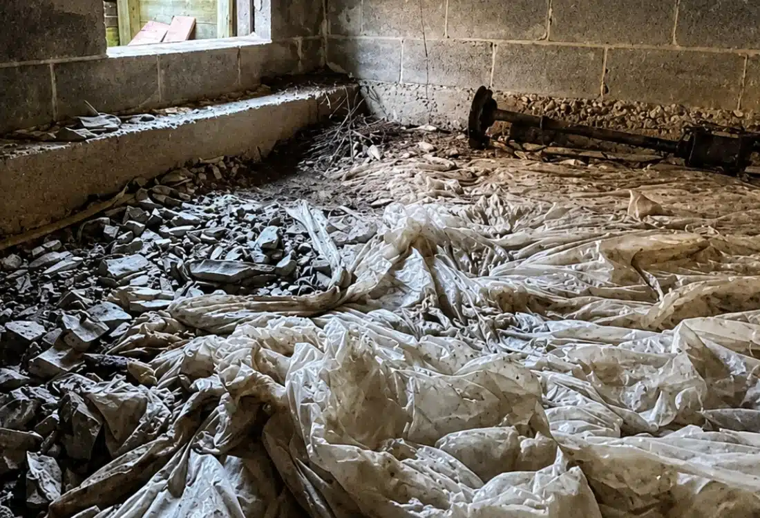 Crumpled deteriorating vapor barrier on a crawl space floor showing degradation that causes cat urine gassing odor in Reston, VA.
