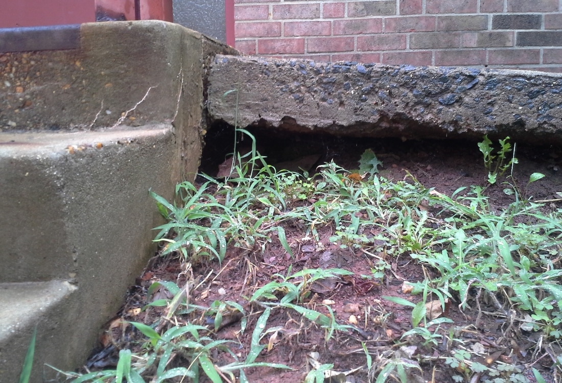 Separated concrete footing and red Virginia clay soil showing foundation settlement that reduces home value in White Post, VA.