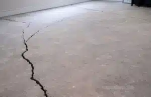 Close-up of visible cracks in basement concrete floor signaling foundation movement in Clear Brook, VA.