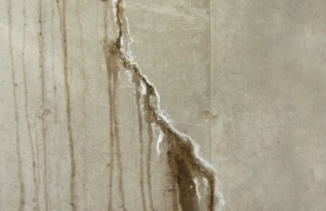 Water seepage through wall crack with efflorescence and rust staining, sign of cracks in basement wall problem in Southbridge, VA.
