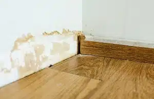 Yellow brown water stains and discoloration on basement baseboard and wall, indicating sign of mold in basement in Ashburn, VA.