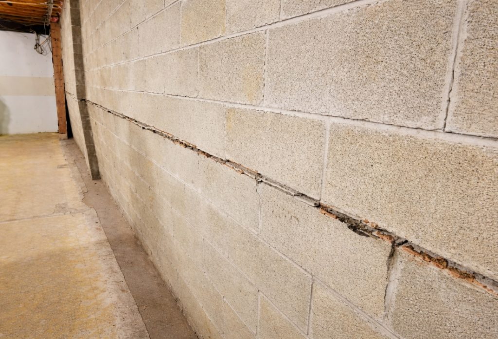 Bowing basement block wall with cracks from hydrostatic pressure, a problem French drains installation fix in Winchester, VA.