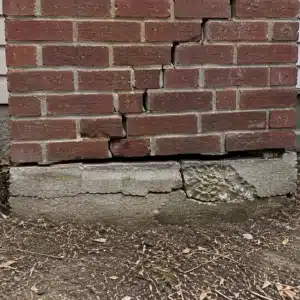 Displaced chimney footing with brick cracking where clay soil movement causing cracks in chimney bricks in Gainesville, VA.