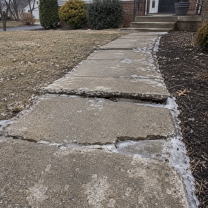 Concrete sidewalk slabs with widened gaps and surface spalling from freeze-thaw cycles, causing uneven sidewalk in Warrenton, VA.