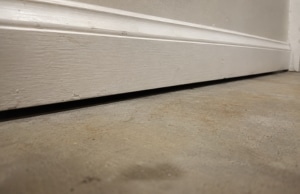 Gap between basement floor and baseboard trim, a sign of uneven basement floor in Bristow, VA, caused by foundation settlement.