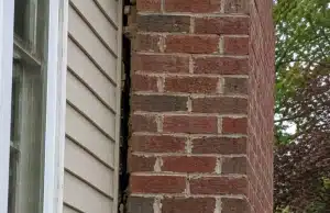Visible gap forming between a brick chimney and house wall, a sign of cracks in chimney bricks problem in Manassas, VA.