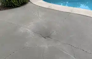 Concrete pool deck section showing stress fractures from soil voids beneath, sign of sinking pool deck problem in Bristow, VA.