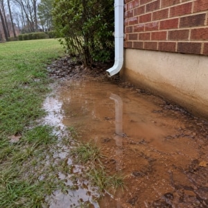 Downspout draining water directly against a foundation wall, causing crack in crawl space foundation wall in Clear Brook, VA.