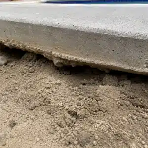 Loose uncompacted soil exposed beneath a lifted concrete pool deck slab causing sinking pool deck problem in Warrenton, VA.