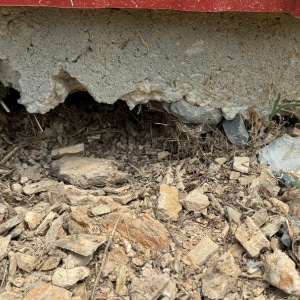 Void forming beneath concrete foundation slab from poor soil compaction causing uneven basement floor in Berryville, VA.