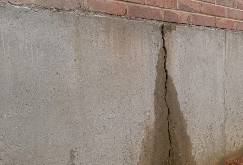 Cracked foundation wall with water staining, a problem French drains help to protect home's foundation in Berryville, VA.