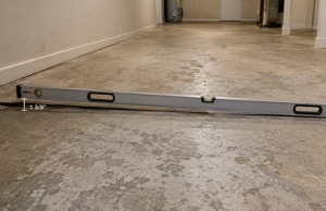 Level tool on uneven basement floor showing unevenness from settlement, a sign of an uneven basement floor in Berkeley, WV.