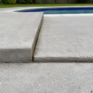 Two concrete pool deck slabs at different heights from soil settlement causing sinking pool deck problem in Southbridge, VA.