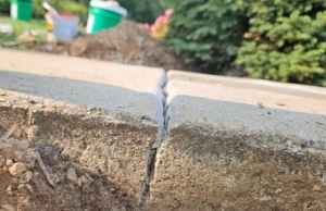 Visible gap and crack separating concrete sidewalk slab sections showing soil movement, a sign of uneven sidewalk in Southbridge, VA.