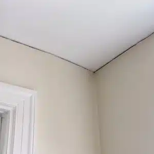 Gap forming where the wall meets the ceiling beside a door frame from structural shifting causing sticking doors in Harpers Ferry, WV.