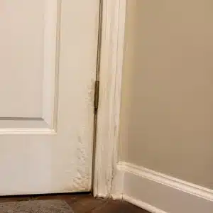 Paint bubbling and moisture staining along a door frame from wood swelling causing seasonal sticking doors in Bristow, VA.