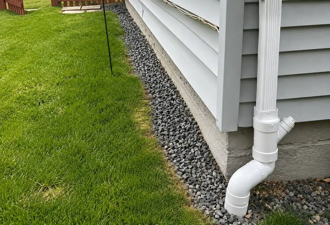 Failed French drain with gravel bed and PVC downspout pipe along foundation wall before exterior waterproofing in Alexandria VA.