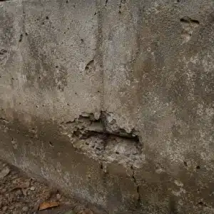 Concrete carbonation and aging on foundation wall from alkalinity loss over time causing chipping concrete in Reston, VA.