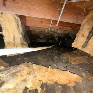 Damaged and deteriorated crawl space insulation hanging from floor joists, causing high electric bills in Linden, VA.