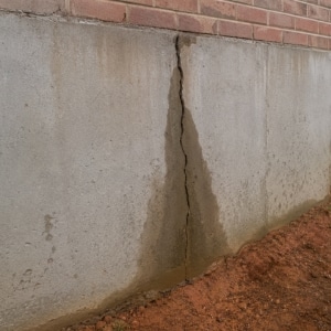 Vertical crack with moisture staining running down a poured concrete foundation wall causing an unlevel floor in Berkeley, WV.