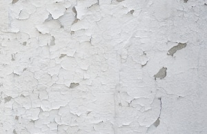White paint flaking off a basement wall in large and small patches, sign peeling or bubbling paint on basement walls in Berkeley, WV.