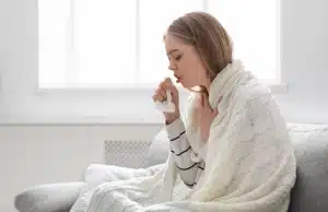 Women coughing indoors due to high humidity and mold allergens below, sign of indoor allergy or asthma problem in Ashburn, VA.